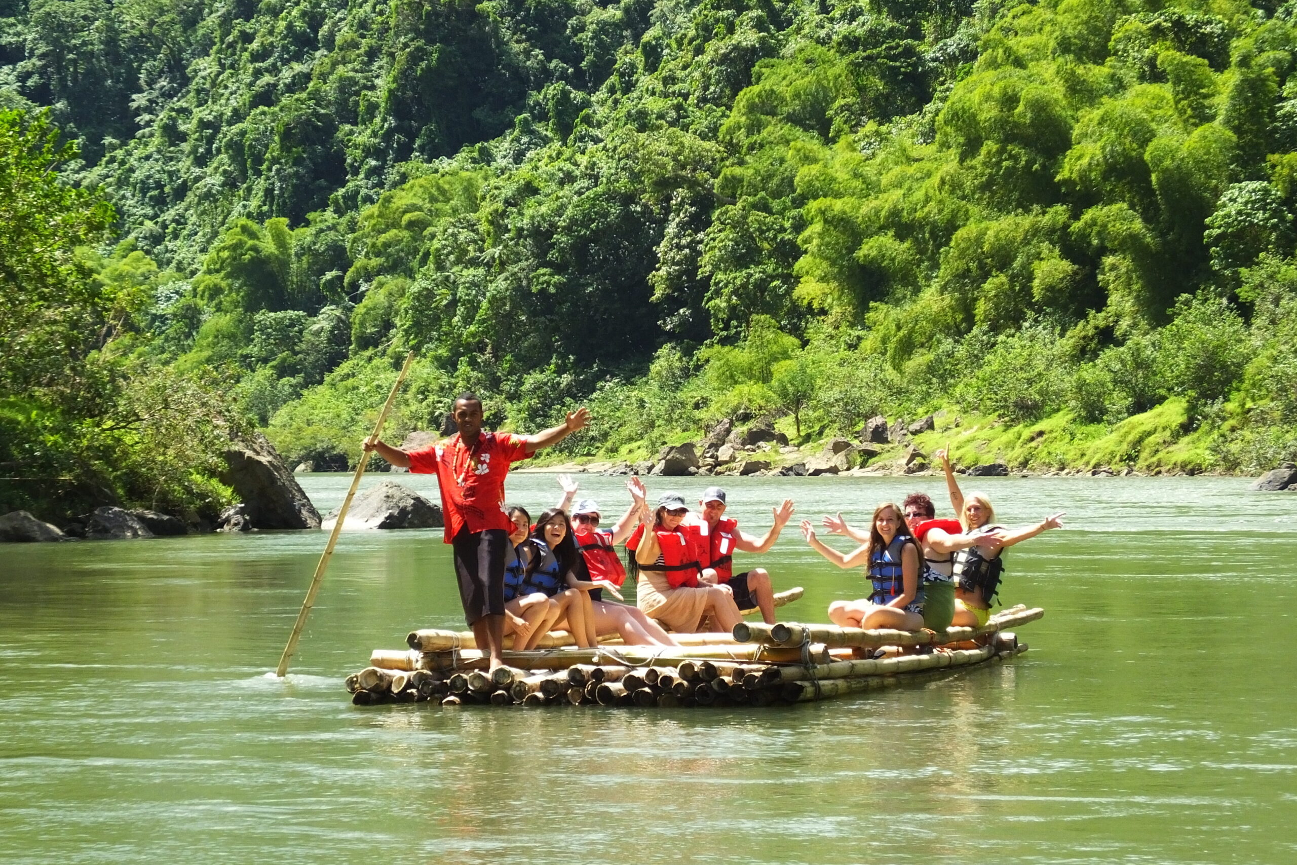 People riding a bamboo raft down a river
