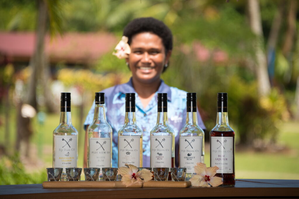 Waidroka staff member standing behind a row of rum bottles at the bar