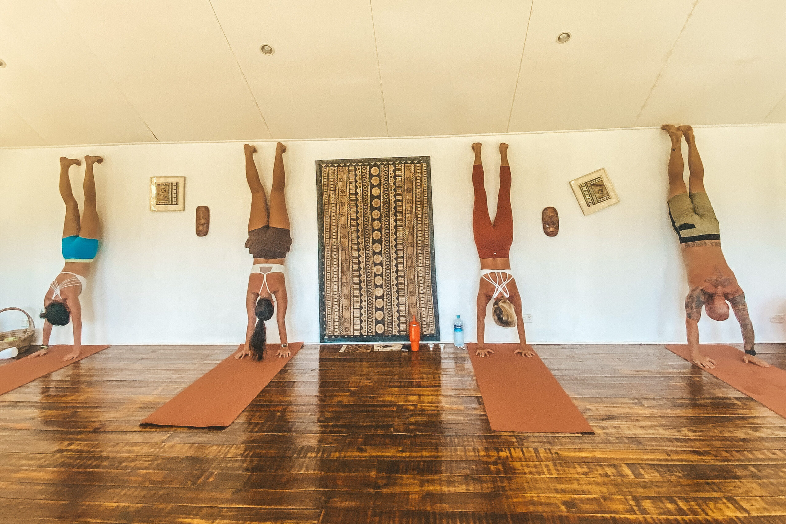 Four people doing hand stands at the Yoga studio at Waidroka Bay Resort